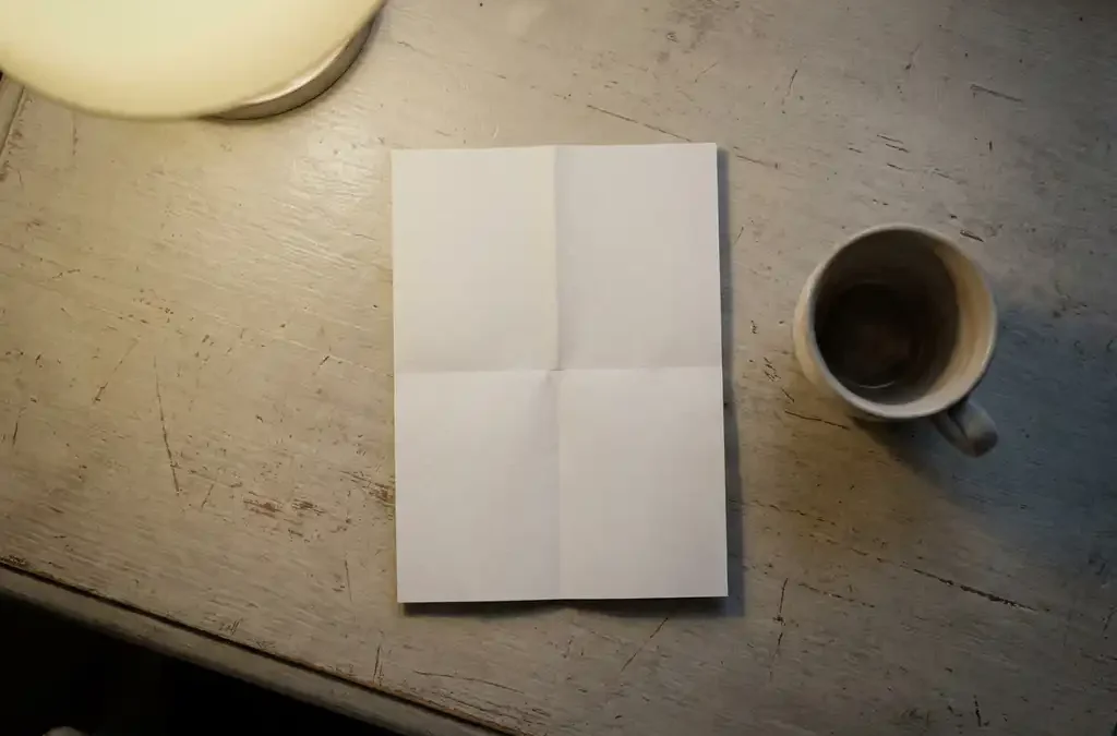 Onbeantwoorde vacature op wit papier naast een leeg koffiekopje op een houten bureau, zachte beige en grijze tinten.